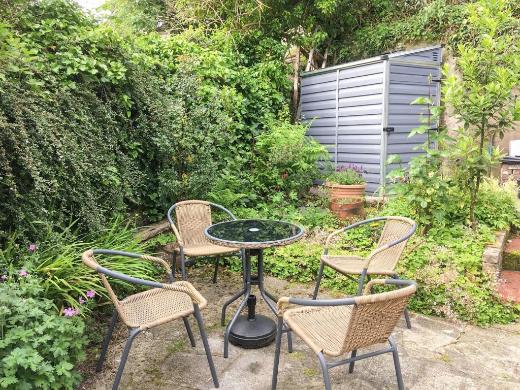 trzy krzesła i stół w ogrodzie w obiekcie Woodville w mieście Porthmadog