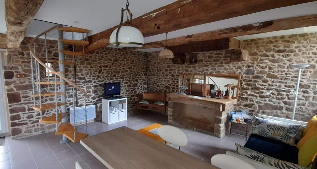 sala de estar con mesa y pared de piedra en Gîte Le Valet, T2 classé 3 étoiles, entre Rennes et Saint-Malo, en La Chapelle-aux-Filzméens