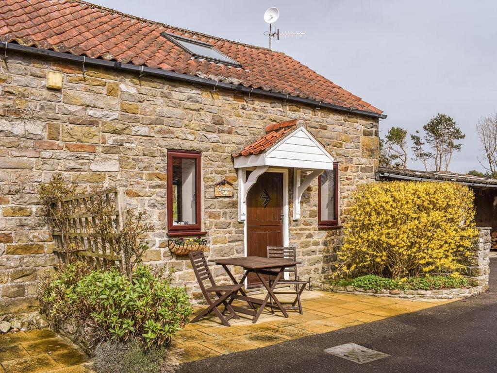 a stone house with a picnic table and an awning at Swallows Folly-uk38278 in Cloughton