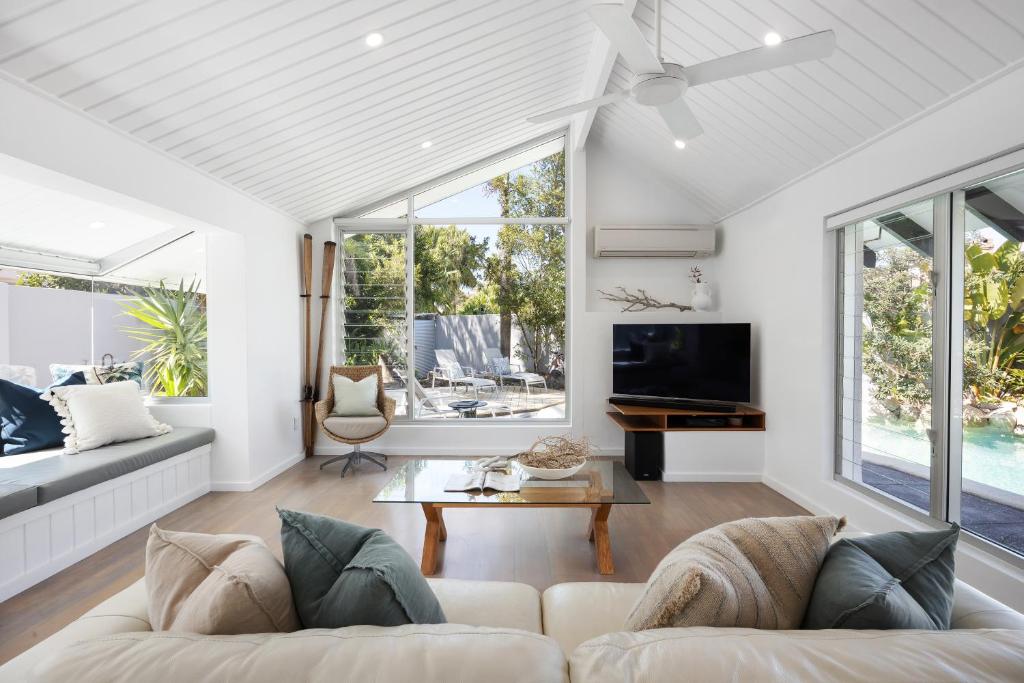 a living room with a couch and a tv at Villa Bianco, 5 Key Court, Noosa Heads in Noosa Heads