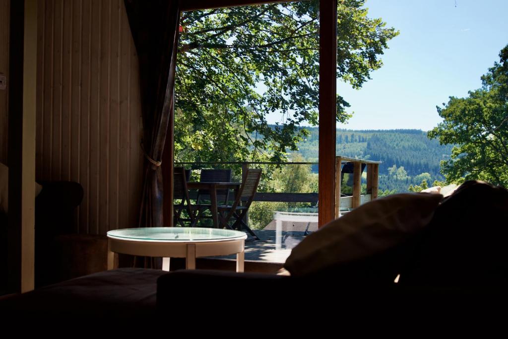 Cette chambre offre une vue sur une terrasse couverte avec une table. dans l'établissement Chalet le Faye, à Waimes