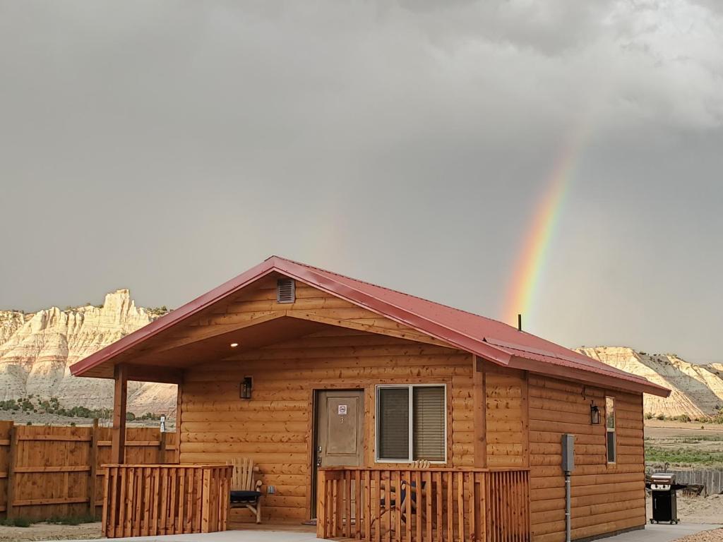a wooden cabin with a rainbow in the background at Log Cottages at Bryce Canyon #3 in Cannonville