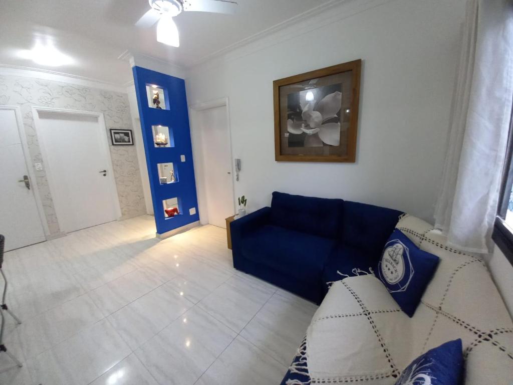 a living room with a blue couch in a room at Ap 2 quartos suite wifi 30m da praia in Guarujá