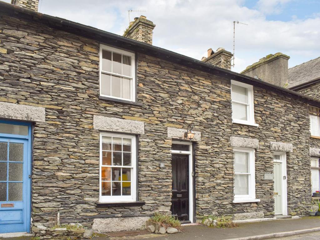 uma casa de pedra com janelas brancas e uma porta azul em Campbell Cottage em Windermere