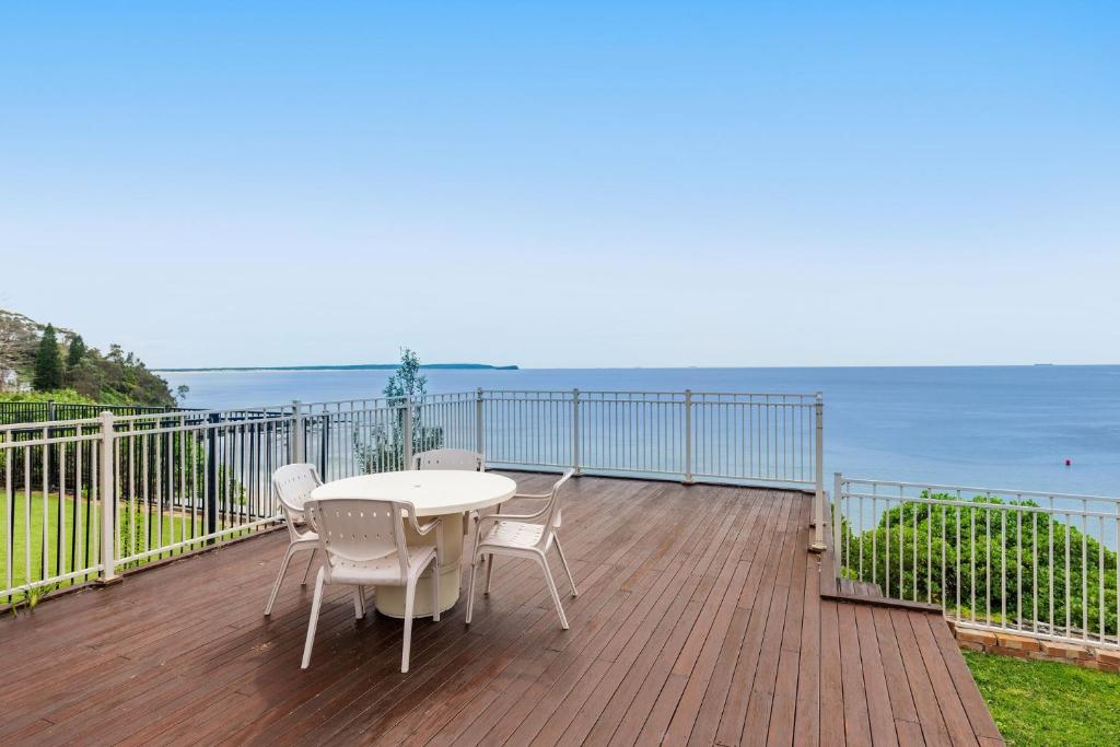 a wooden deck with a table and chairs and the ocean at Norah Head Seascape in Norah Head