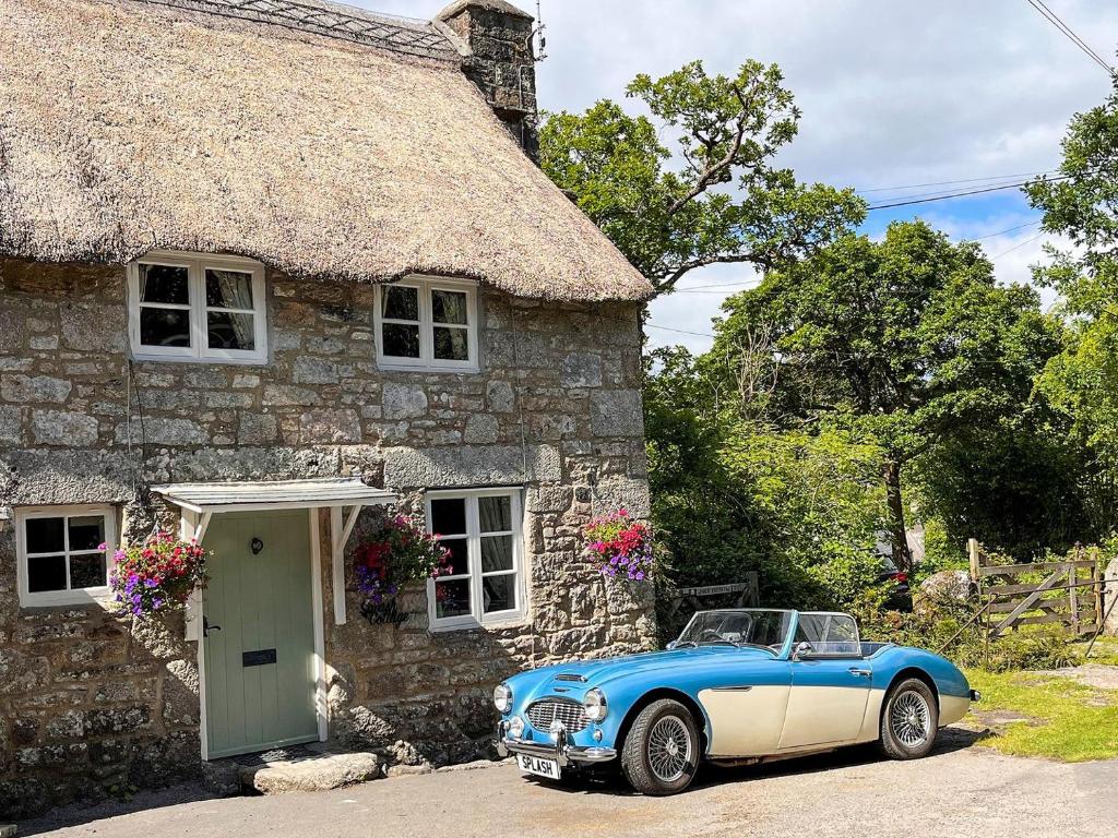 a blue car parked outside of a stone house at Splash Cottage in Widecombe in the Moor