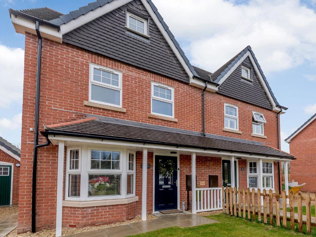 a red brick house with a black roof at Honey Bee House in Woodhall Spa