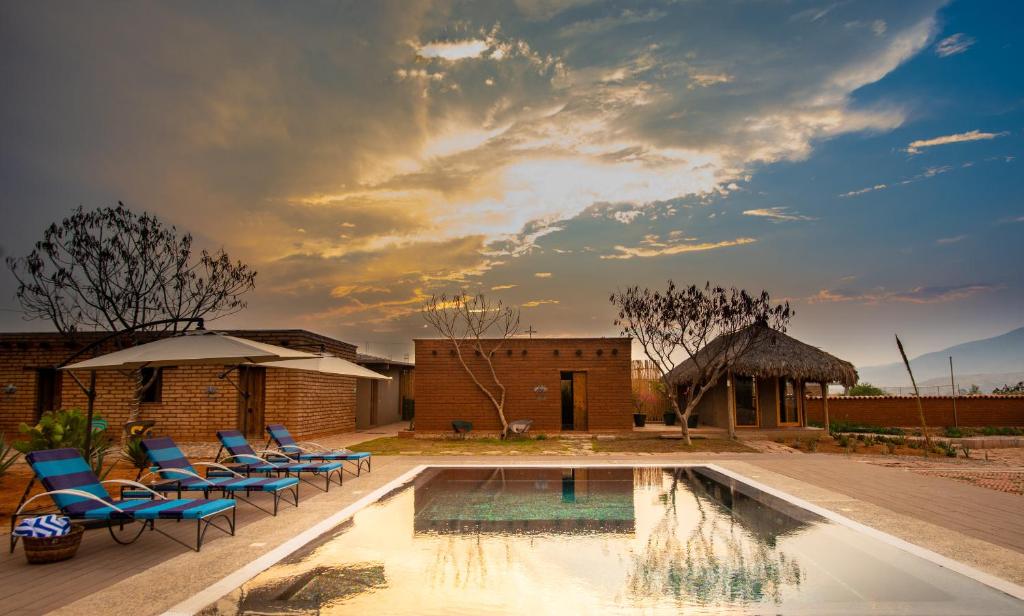 une piscine avec des chaises bleues et un bâtiment dans l'établissement Casa Regina Oaxaca, à San Pablo Villa de Mitla