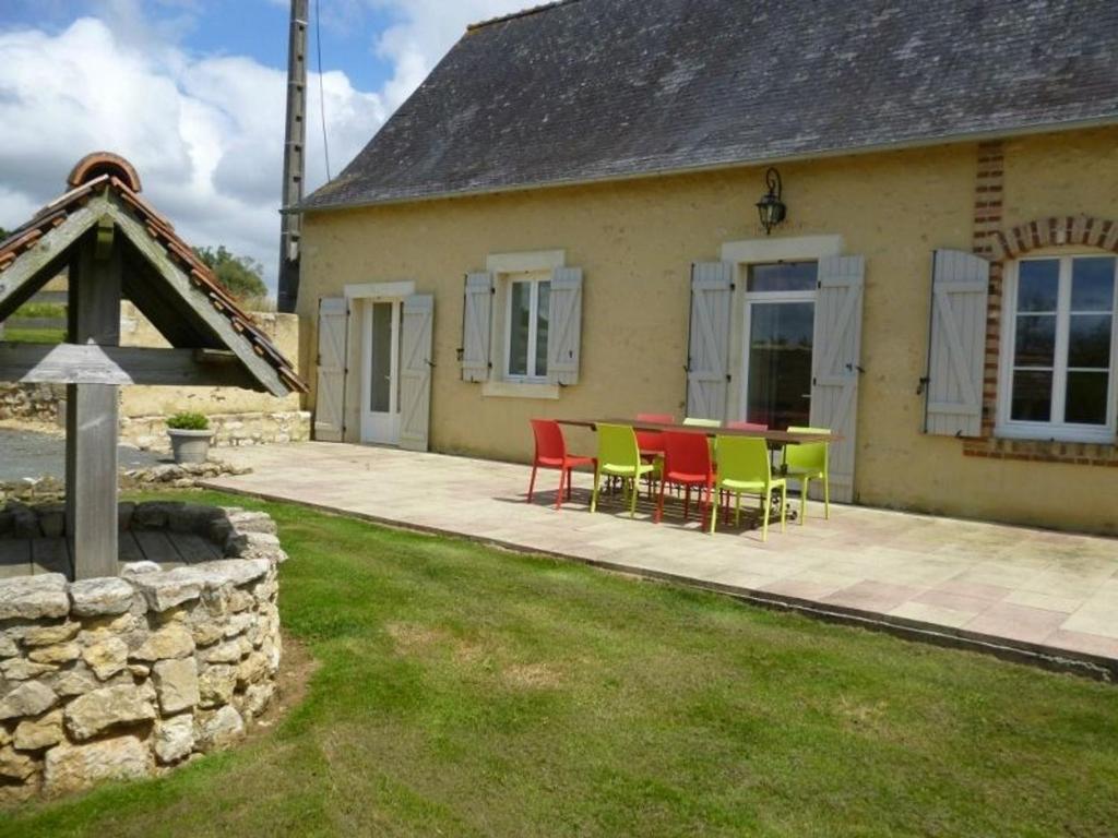 eine Terrasse mit roten und grünen Stühlen vor einem Haus in der Unterkunft Gîte Saint-Christophe-en-Champagne, 5 pièces, 8 personnes - FR-1-410-192 in Saint-Christophe-en-Champagne
