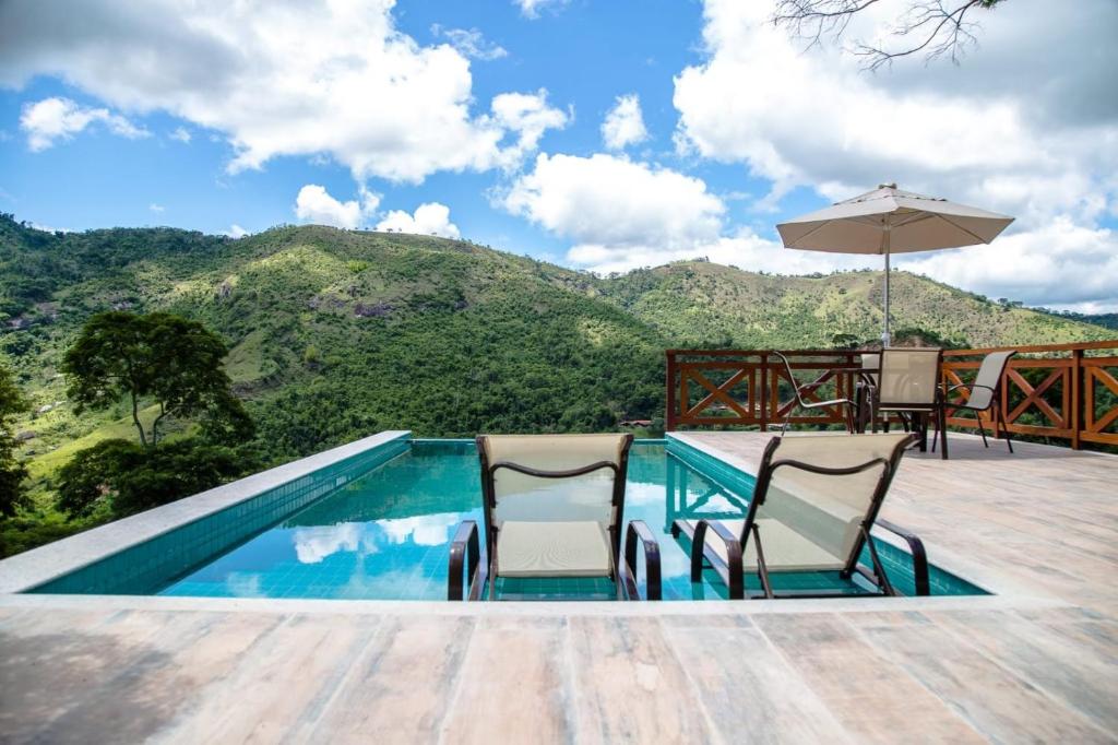 una piscina con sillas, una sombrilla y una montaña en Bela vista - Secretário en Petrópolis