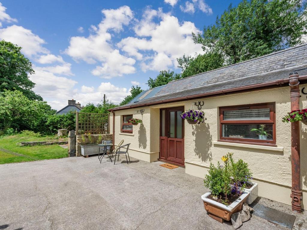 a cottage with a table and chairs in front of it at Llanfair Hill Cottage in Cwrt-newydd