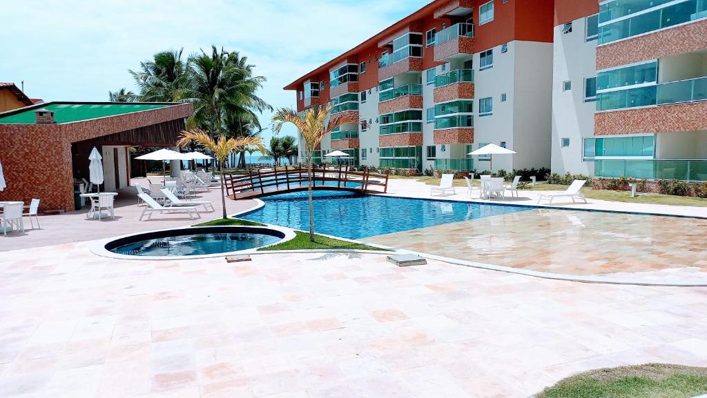 a swimming pool in front of a building at Apartamento Pé na areia em Tamandaré-Porto Cayman in Tamandaré