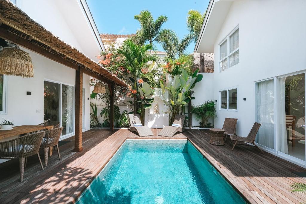 a villa with a swimming pool and a wooden deck at Sun & Moon Villa in Canggu