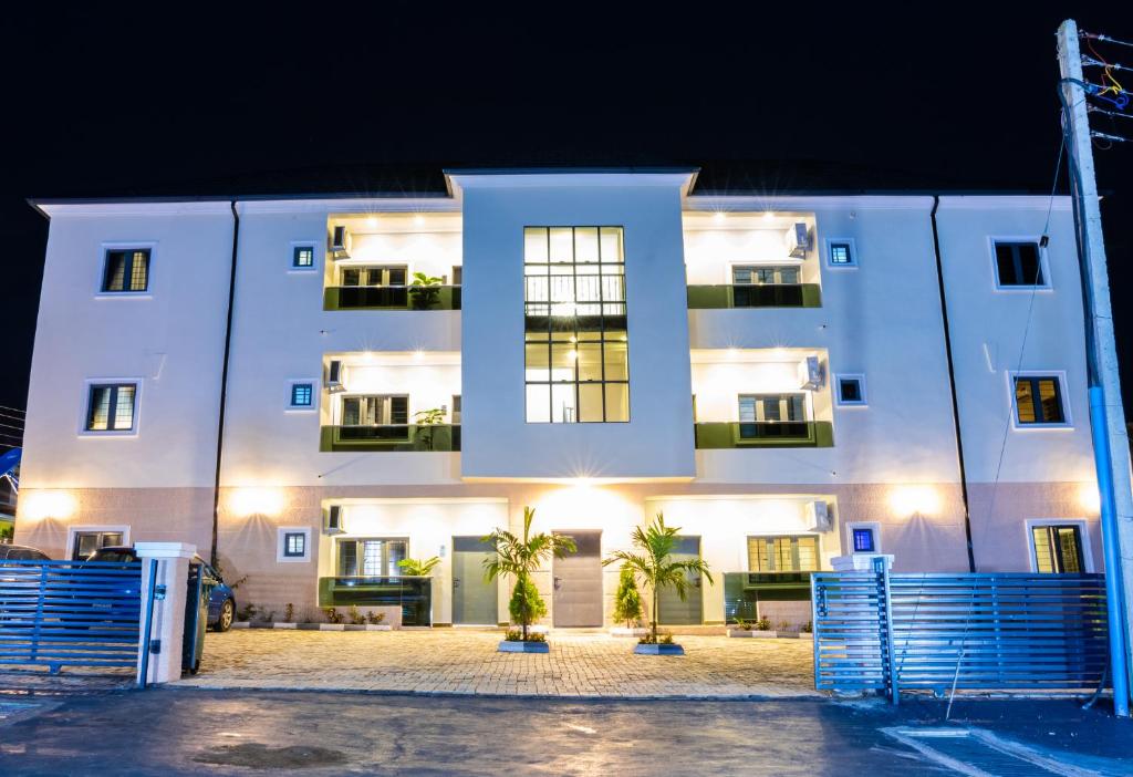 un edificio blanco por la noche con palmeras delante en 99 MOZILLA APARTMENTS AND SUITES en Abuja
