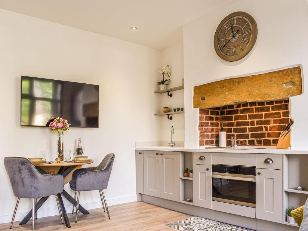 a kitchen with a table and a clock on the wall at Redmonds Retreat in Chinley