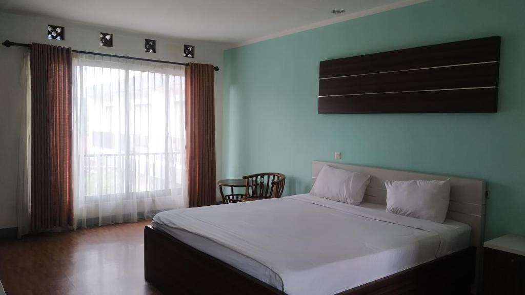 - une chambre avec un grand lit blanc et une fenêtre dans l'établissement PUNCAK VILLAGE HOTEL & KAMPUNG MAIN ANAK, à Gadok 1