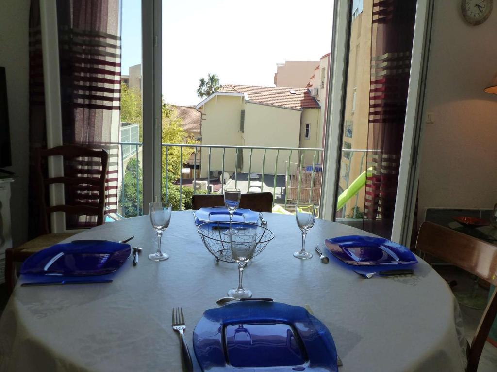 - une table avec des assiettes bleues et des verres à vin sur un balcon dans l'établissement Appartement Climatisé au Centre du Lavandou, 3 Chambres avec Balcon, Proche Commodités - FR-1-308-157, au Lavandou