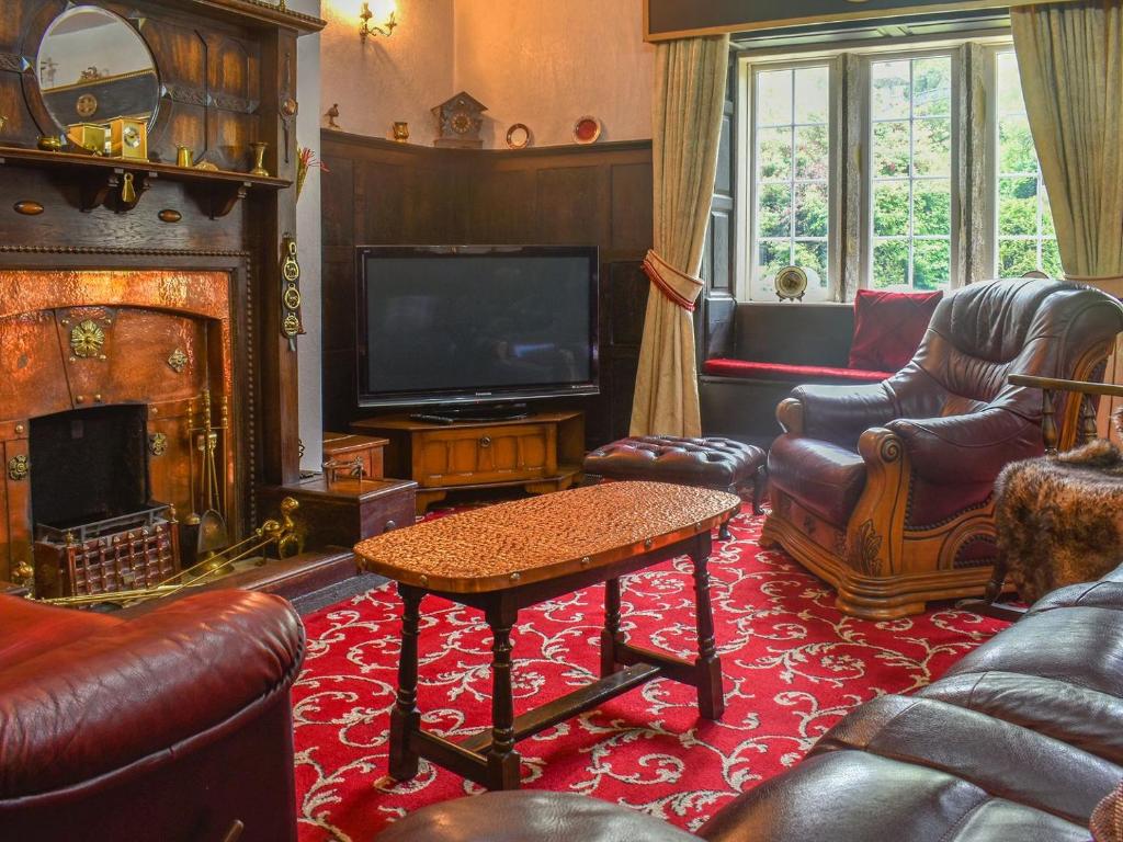 a living room with leather furniture and a tv and a fireplace at Foxstones Farm House in Worsthorne