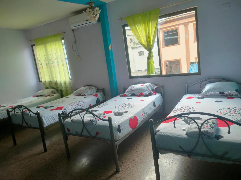 a room with three beds and two windows at Hotel Eloy Alfaro in Guayaquil