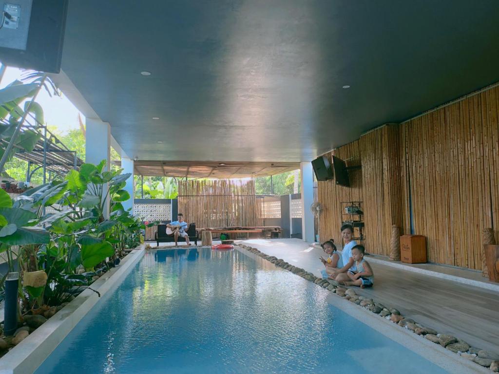 two children sitting on the edge of a swimming pool at Nha Bong Villa in Hoi An