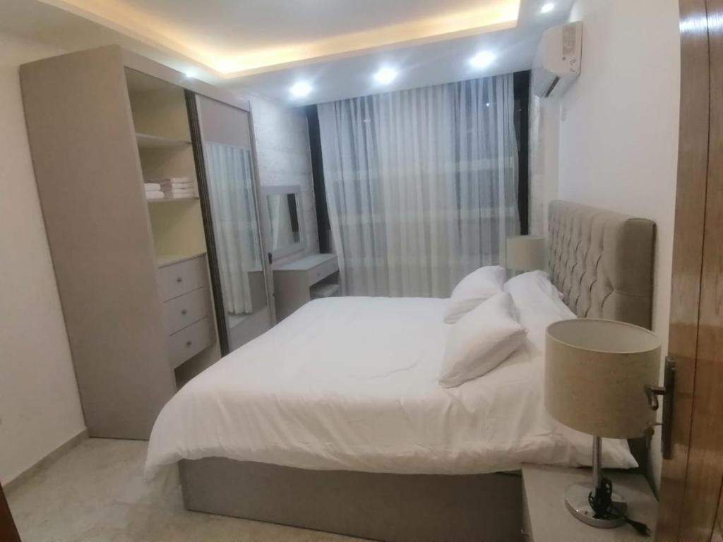 una camera con letto bianco e specchio di Executive Apartments ad Amman