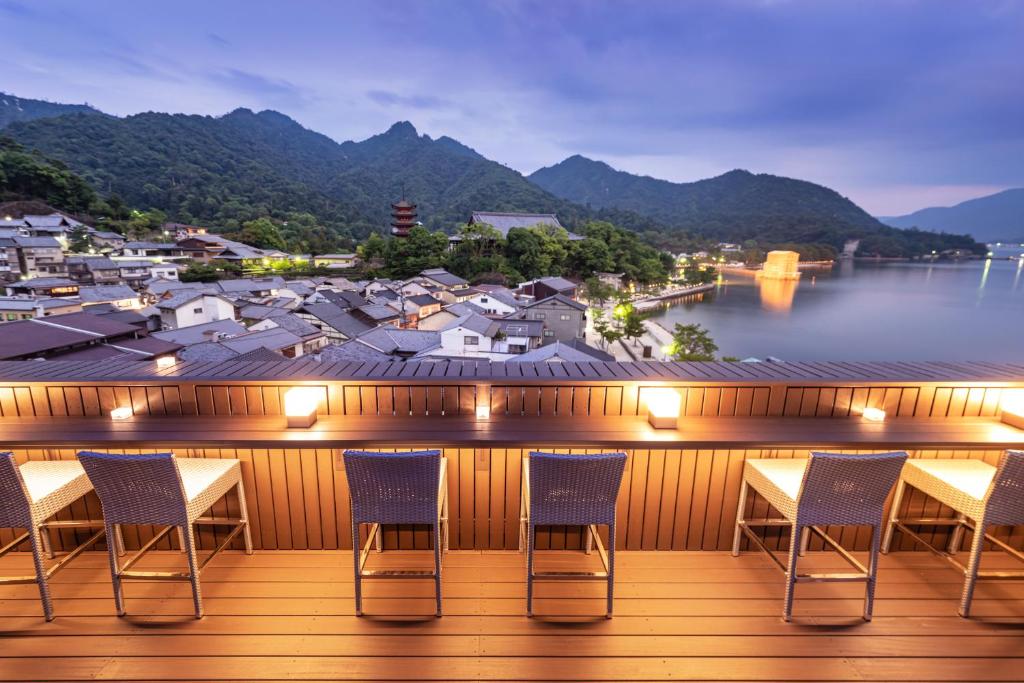 a balcony with chairs and a view of a city at Kinsuikan in Miyajima