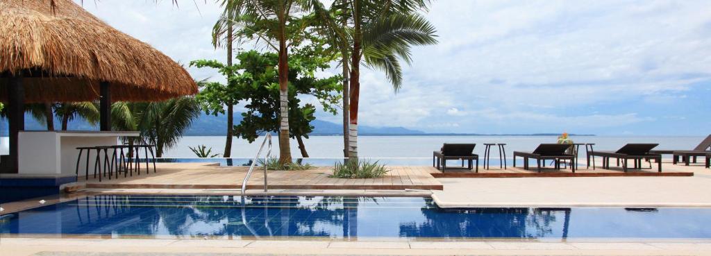 a swimming pool with a table and chairs and the ocean at Hijo Resorts Davao in Tagum