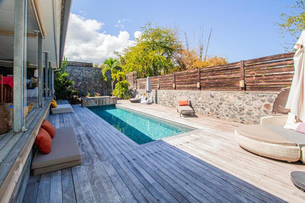 une arrière-cour avec une piscine et une terrasse en bois dans l'établissement Couleur Sables - belle villa avec piscine chauffée - St Gilles les Bains Grand Fond, à Saint-Gilles les Bains
