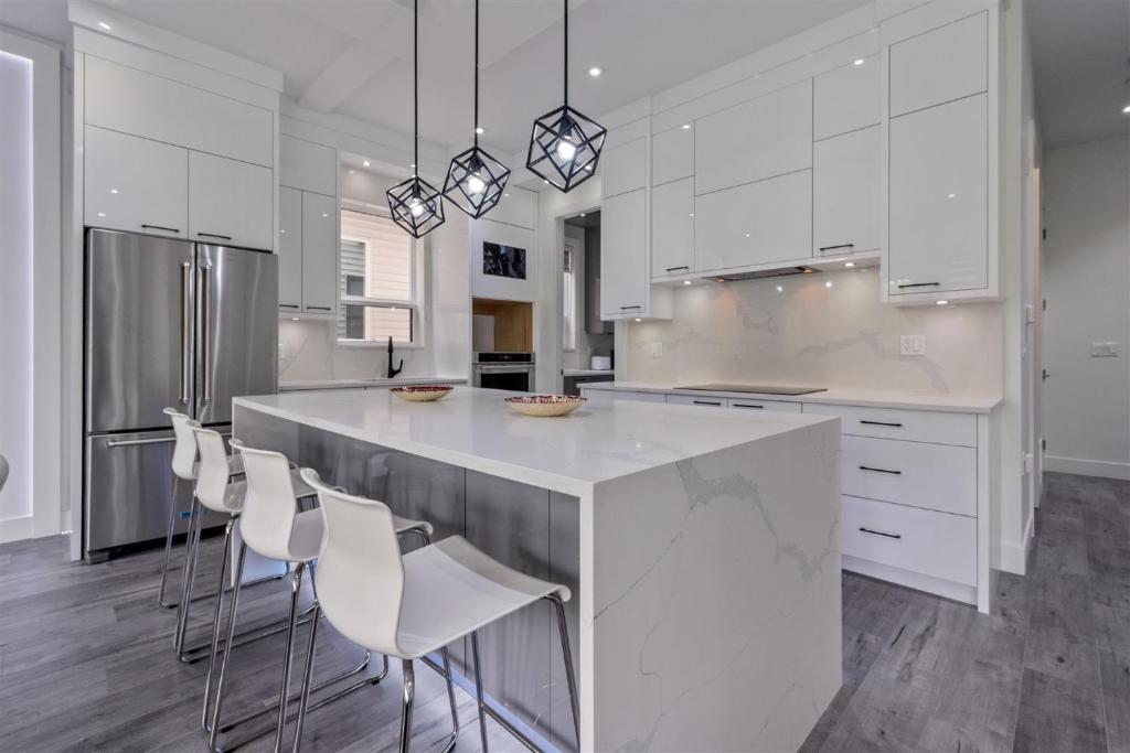 a kitchen with white cabinets and a large island with chairs at Brand New, Cheerful, Exquisite 4 BR house, fast wifi, free parking in Langley