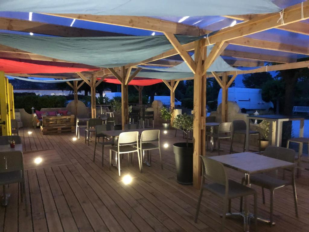 una terraza con mesas y sillas por la noche en Logis hôtel restaurant Le clos saint loup en Bram