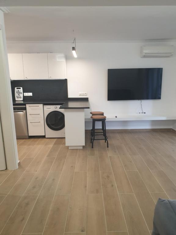Pokój z kuchnią i telewizorem na ścianie w obiekcie Newly Renovated Varkiza Beachside One Bedroom with Large Terrace w Atenach