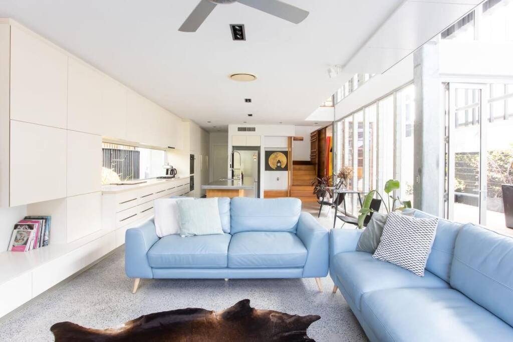 Casuarina Beachfront House - Hostie Properties في ساحة كاسوارينا: غرفة معيشة مع أريكة زرقاء وكلب ملقى على الأرض