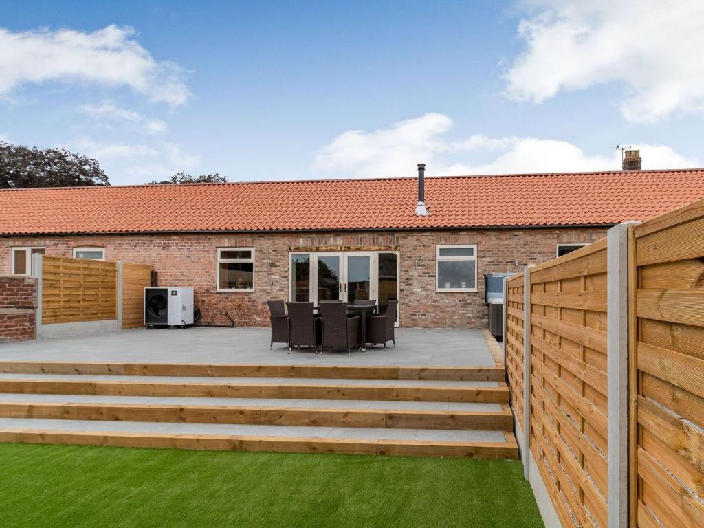 a garden with a wooden fence and a patio at Dip Tub Den - Uk35989 in Wansford