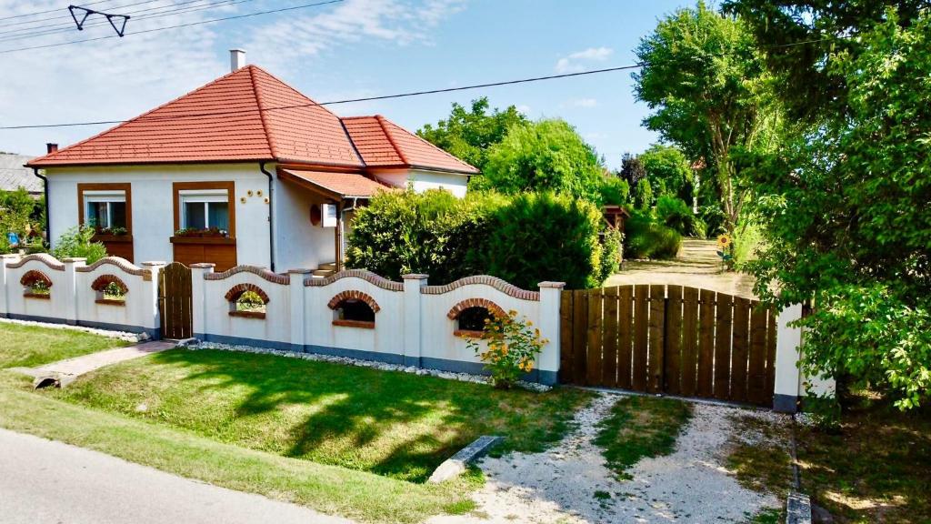 una casa blanca con una valla y un patio en Döre Vendégház, en Bakonyszentlászló