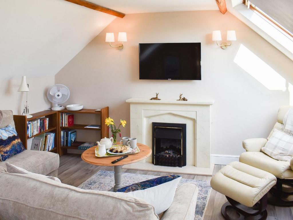 a living room with a fireplace and a tv at The Stables in Bealings