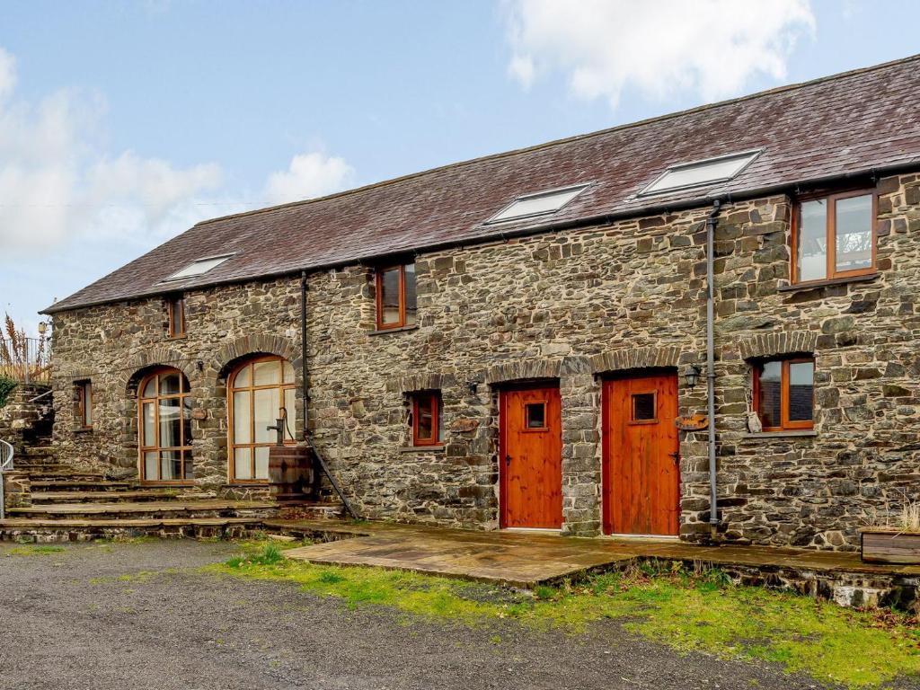 an old stone building with red doors and windows at Robins Nest - Uk36208 in Llanfihangel-y-creuddyn