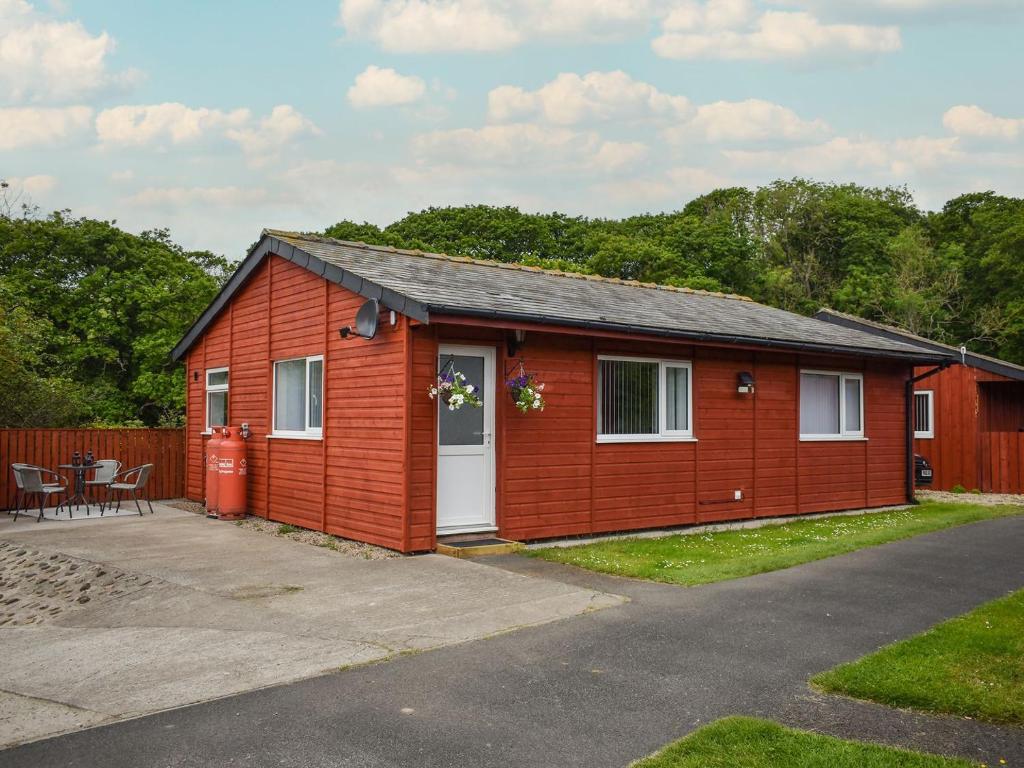 a small red house with a table and a patio at Bumblebee Lodge in Staithes