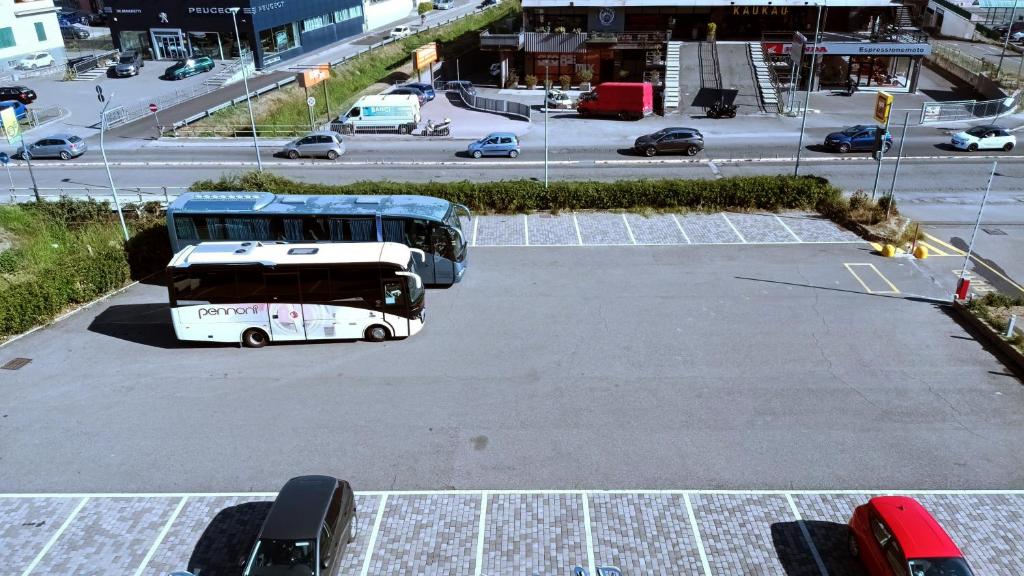 dos autobuses están estacionados en un estacionamiento en Hotel Al Sant'Andrea, en Sarzana