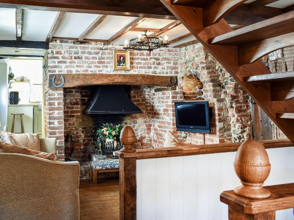 uma sala de estar com uma parede de tijolos em Canons Hall Cottage em Wingham