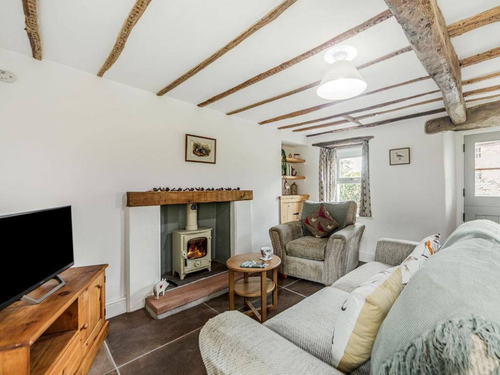 a living room with a couch and a fireplace at Wrens Beck Cottage in Ousby