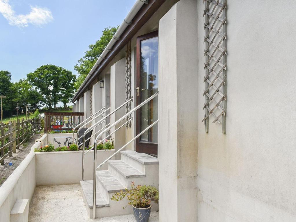 a white building with stairs and a window at Dairy Cottage - Uk37833 in Pillaton