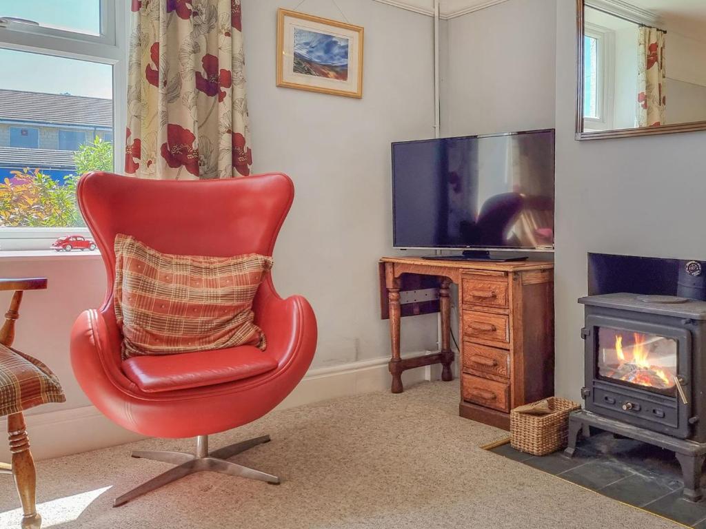 una silla roja en una sala de estar con TV en Pear Tree Cottage, en Bath