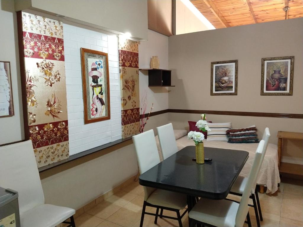 a dining room with a black table and white chairs at Departamentos San Pedro in San Pedro