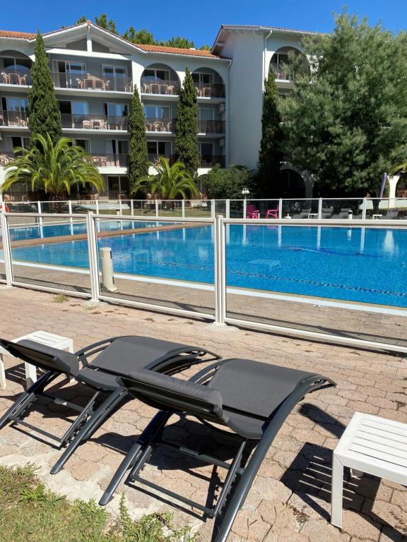 a table and chairs next to a swimming pool at Hotel Résidence Anglet Biarritz-Parme in Anglet