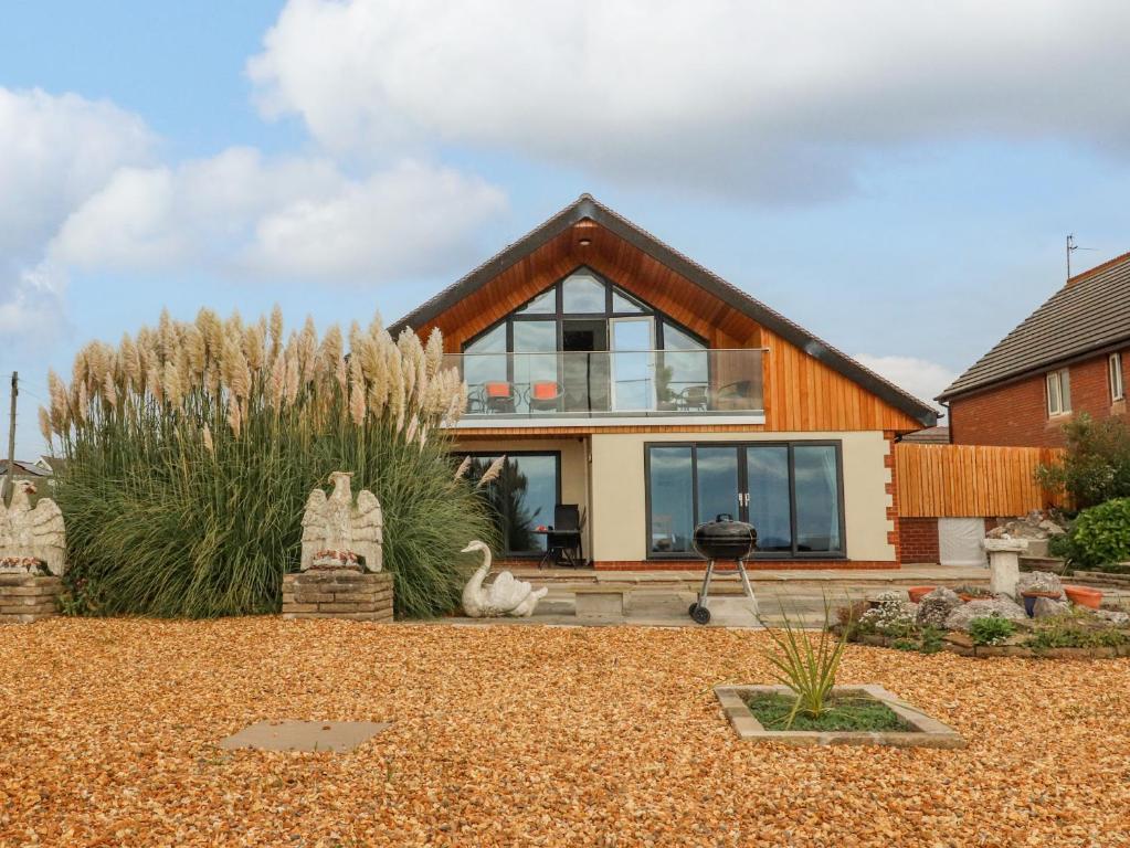 a house with glass windows and a yard at Sea La Vie in Lytham St Annes