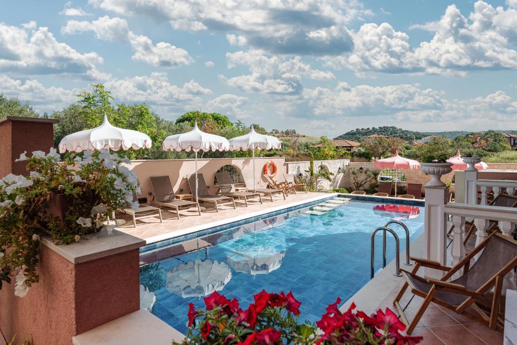 a resort pool with chairs and umbrellas on a balcony at Kseynasa Suites in Nikiti