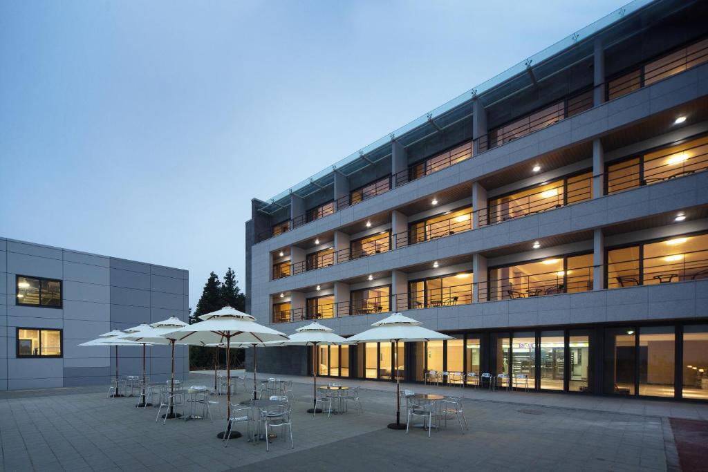 a building with tables and umbrellas in front of it at Luceville in Seogwipo