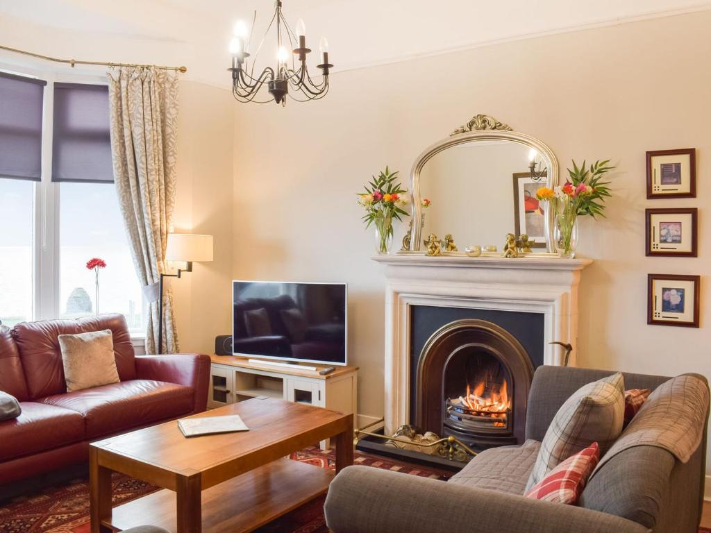 a living room with a fireplace and a tv at Mainslea - Uk36872 in Dunure