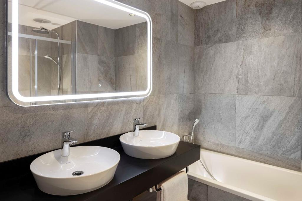 a bathroom with two sinks and a mirror and a tub at HIGALIK HOTEL in Les Menuires