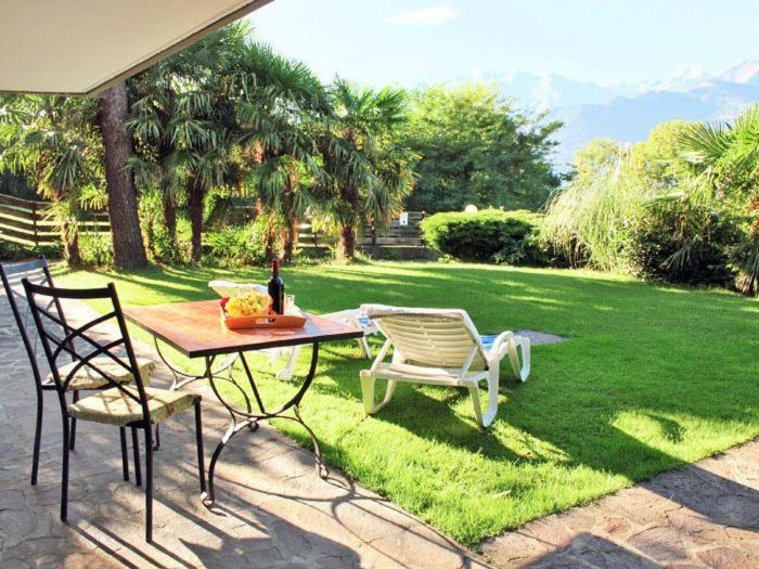 einen Tisch und Stühle auf einem Rasen mit einer Flasche Wein in der Unterkunft Bellavista B Garten-Appartement mit Pool in Colico